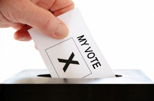 Hand putting a voting slip into a ballot box. You need to register for the Hobbayne by-election