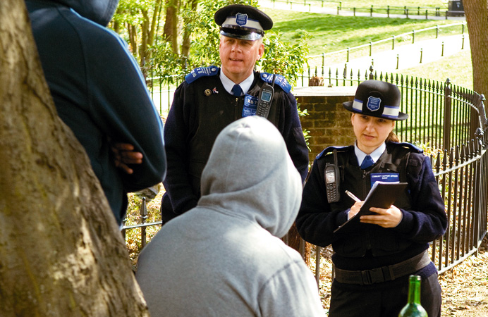 Officers talking to people with drink in a public park