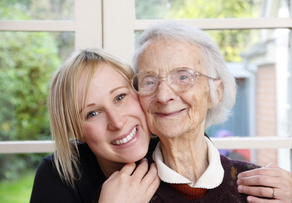 Older woman and younger woman, both white, hugging