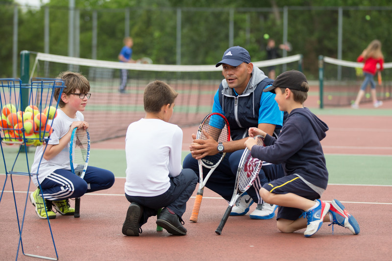 Tennis coach with children learning how to play