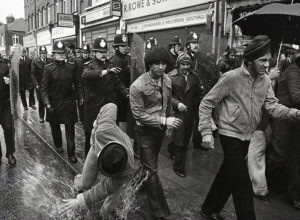 Police knock local man during Southall riot 23 April 1979. Photo by John Sturrock