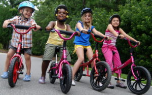 Four young children happily posing on bikes