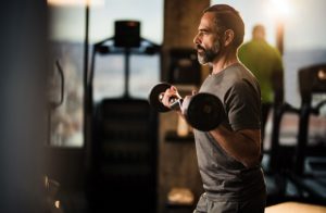 Determined mature man exercising with barbell in a health club.