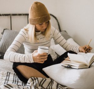 Woman sitting on a bed wearing a brown woolly hat