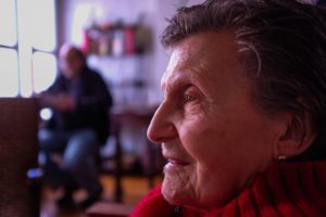 Close up of older woman, with man blurred in the background