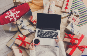 person with lap top surounded by gifts