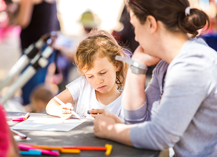 Small child colouring with an adult