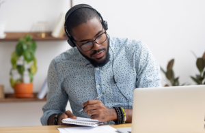 man looking at computer and taking notes