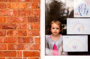 A young girl surrounded by artwork produced during the COVID pandemic