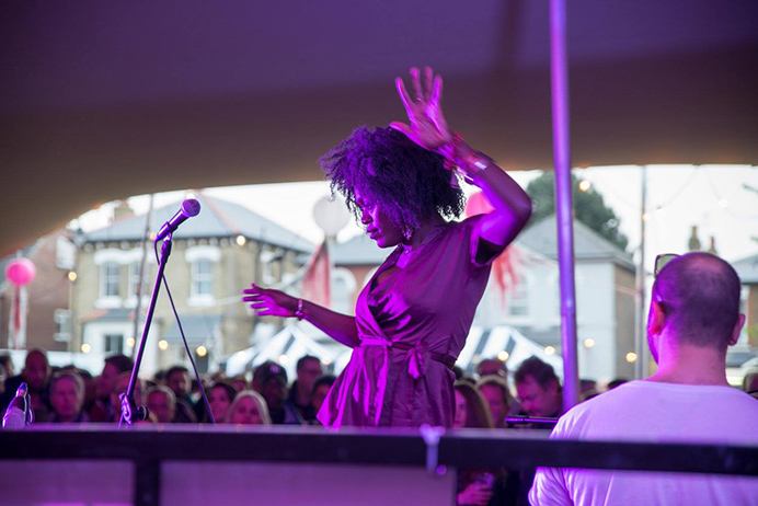 A singer dancing while performing at the Hanwell Hootie, with crowds behind looking on