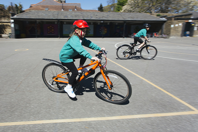 A girl school pupil riding a bike in a playground