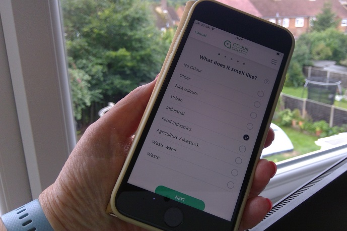 Hand holding iphone showing Odour Collect App