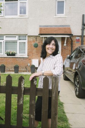 Woman standing at the end of a driveway in front of her house