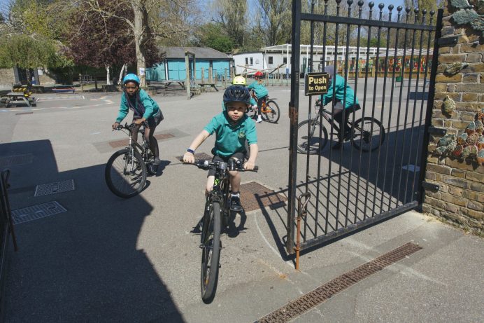 School pupils riding bikes through school gates