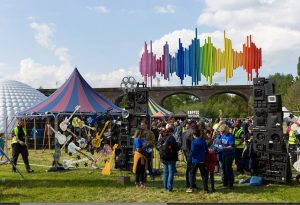 People entering the Hanwell Hootie music festival entrance. In the background is a colourful big top tent