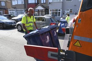 Recycling truck and bin collectors in a street collecting recycling from bins