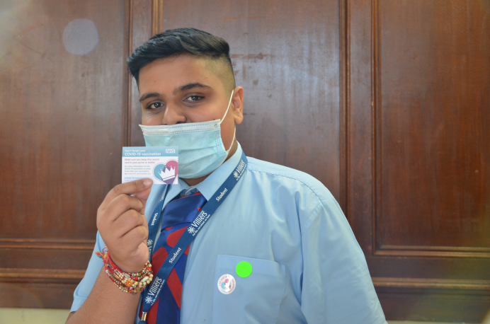 A school pupil holding up his vaccination card