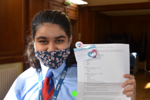 School pupil holding up a vaccination card after having the jab