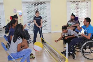 Disabled people in wheelchairs and sitting on chairs, playing volleyball