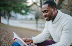 A man reading a book outdoors