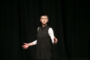 Comedian Fiona Clift mid performance in front of black background