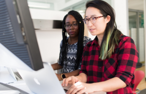 Two women sitting next to each other looking at a computer screen