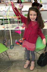 girl holding up mobile that she has created