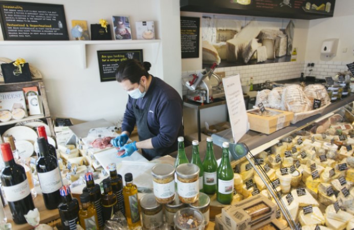 man packaging salami behind deli counter