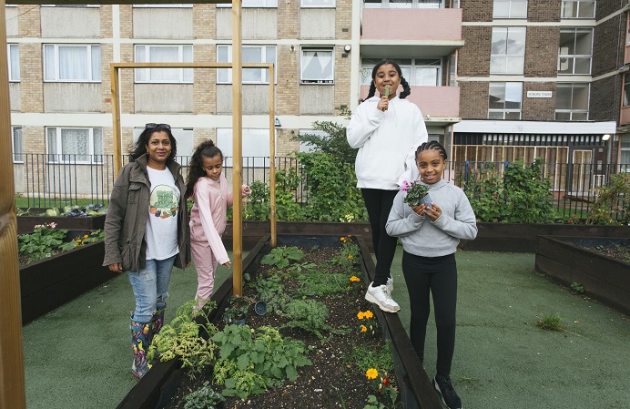 Dina Tsuro and her children alongside an urban garden with vegetables