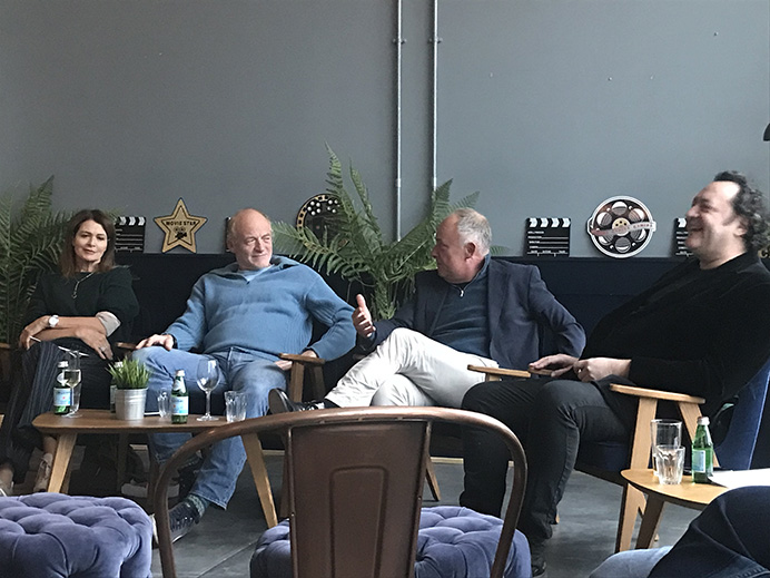 Three men and a woman sitting in armchairs having a discussion