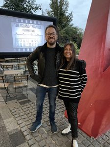 Man and woman standing together in front of a big screen saying Island Triangle Film Festival