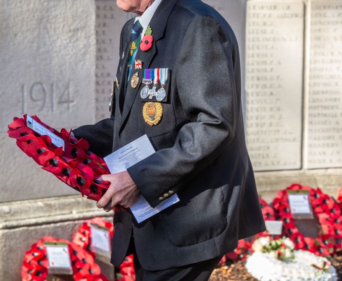 Armed forces veteran wearing medals, carrying a wreath to lay at Ealing War Memorial