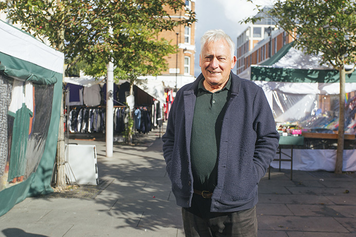 Man standing in outdoor market, with stalls behind him