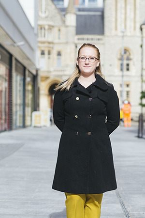 Woman standing in pedestrianised alleyway near cinema and council building