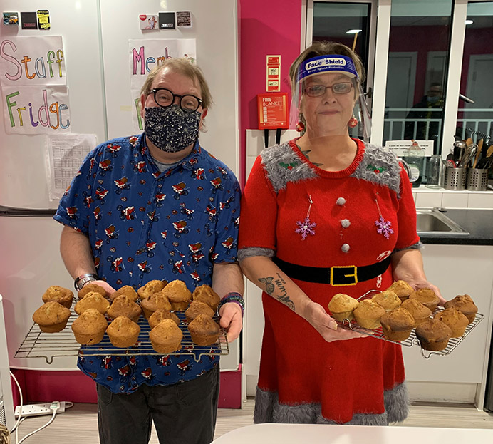 Man and woman standing in kitchen with freshly baked muffins in their hands