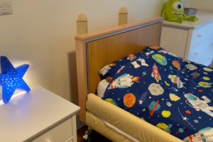 Child's bed featuring a star-coloured duvet and blue star lamp shade