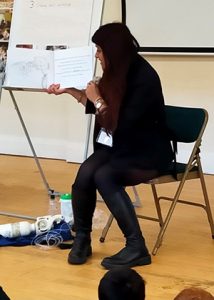 A woman reading a book to children at school