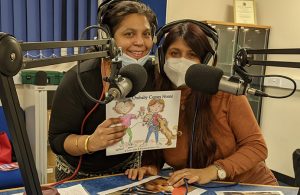Two women holding a book, in a radio studio