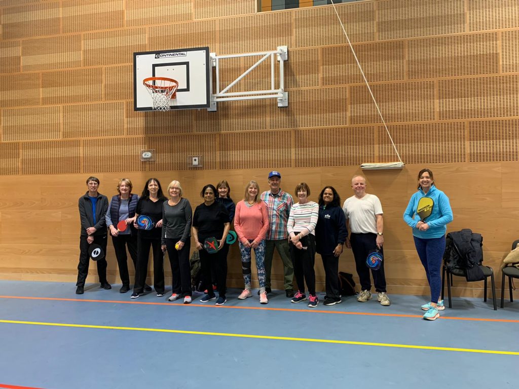 A line of people smiling underneath a basketball hoop