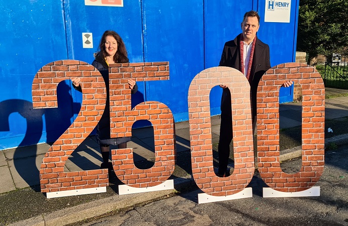 Cllrs Mason and Wall standing behind 2500 figures to celebrate reaching the council's genuinely affordable homes target