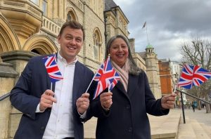 Ealing Town Hall background, Cllrs Peter Mason and Jasbir Anand waving small union flags