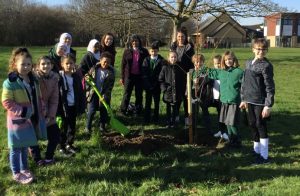 Pupils and teachers planting a tree in a school field