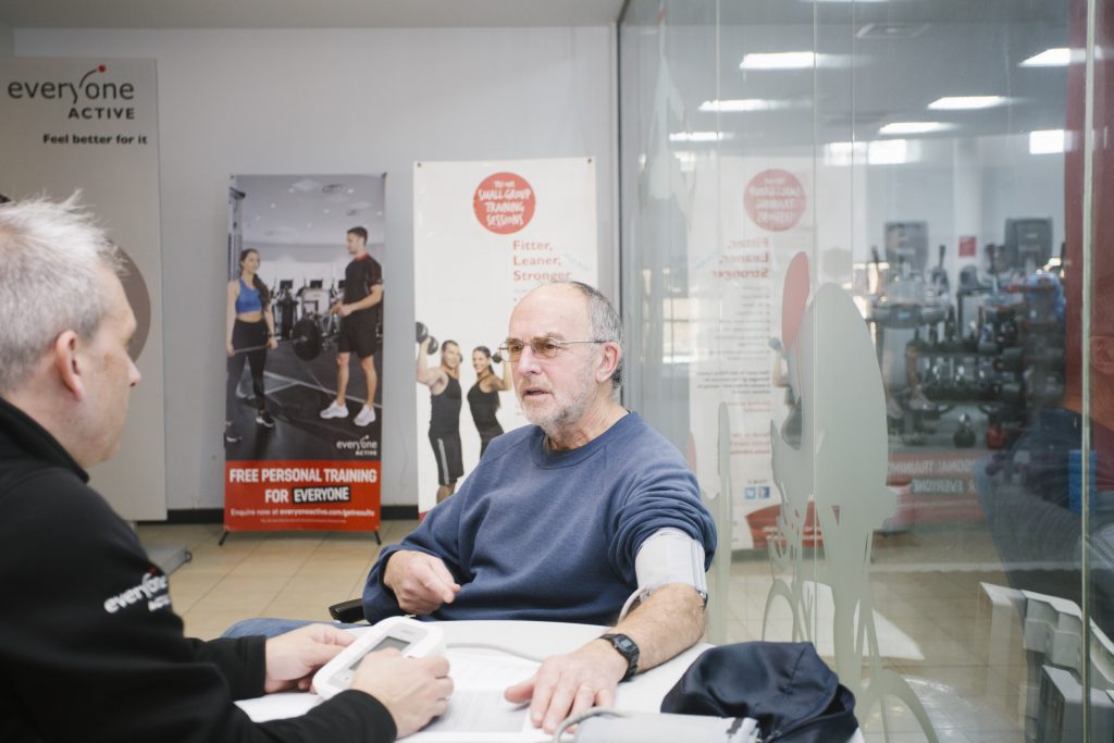 Man sitting at a table chatting while his blood pressure is checked