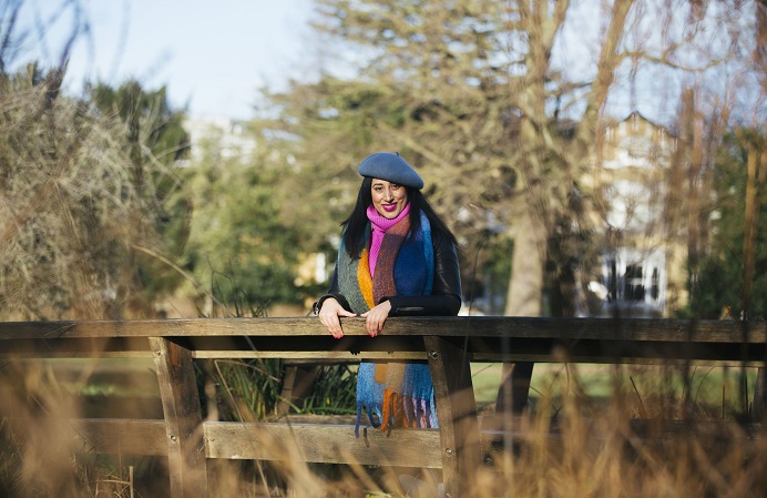 A woman poses in a local park amangst the trees on a sunny day