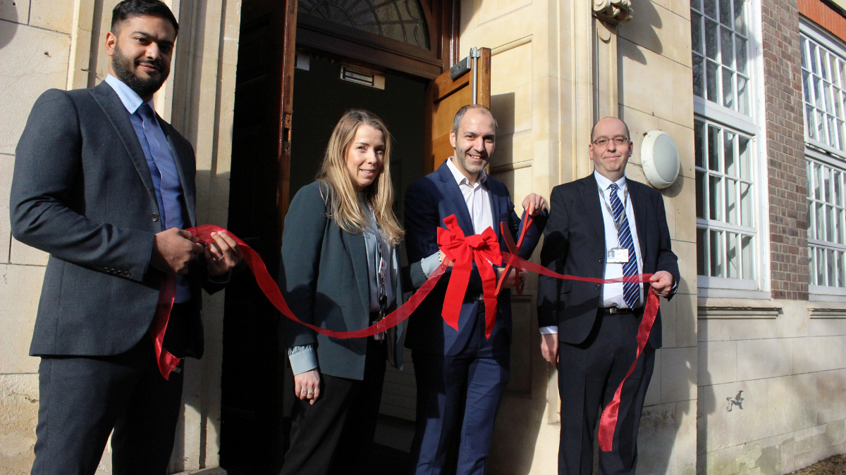 A group of people with a red ribbon at the hub's opening