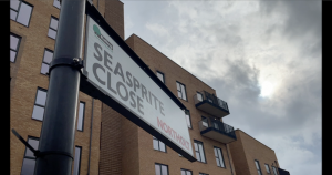 Road sign showing Seasprite Close with apartment block in background