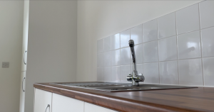 Kitchen sink with tap and white ceramic tiles in the background