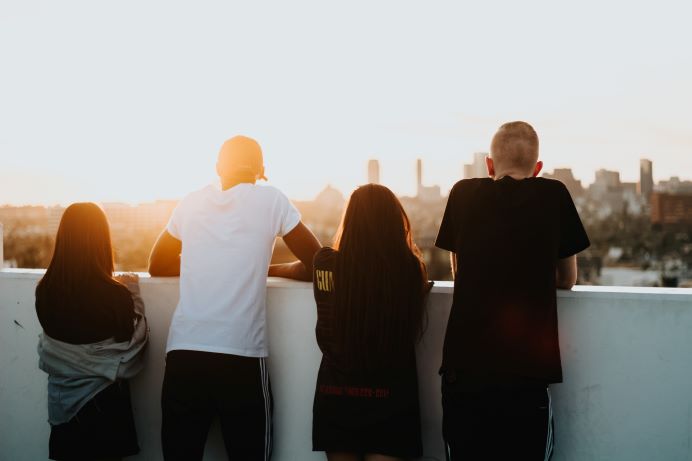 Four young people - two male and two female - looking over a balcony into the distance
