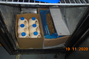 6 plastic milk carts in a cardboard box in a fridge