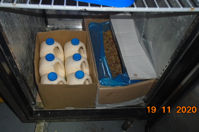 6 plastic milk carts in a cardboard box in a fridge